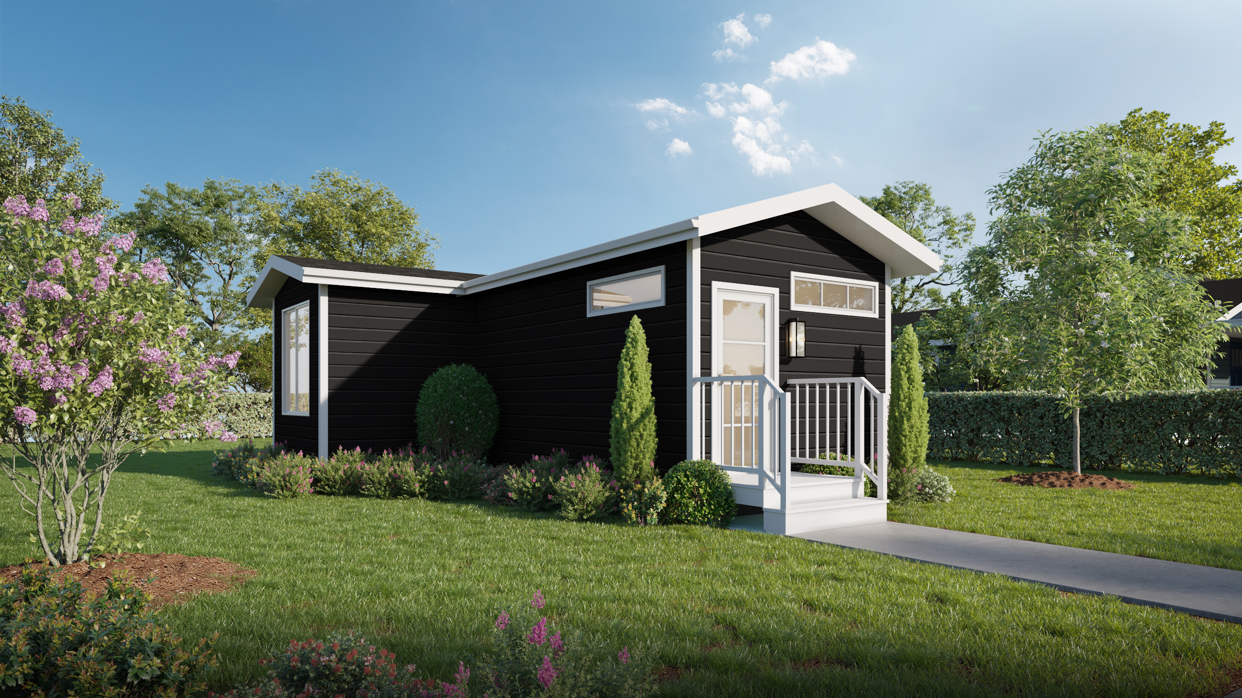 A small black modern tiny house with white trim sits on a grassy lawn, surrounded by shrubs, flowers, and trees under a clear blue sky.